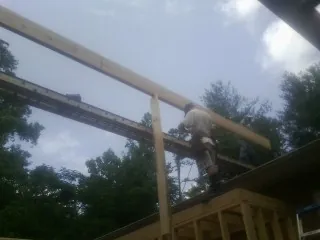 Carpenter setting a ridge beam over a new addition frame — Ice Dam Removal by Roofing Brothers in Watkins