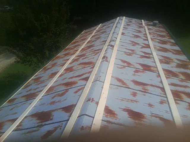 Rusted metal roof panels with new wood purlins before replacement — Storm Damage Roof Repair in Watkins by Roofing Brothers
