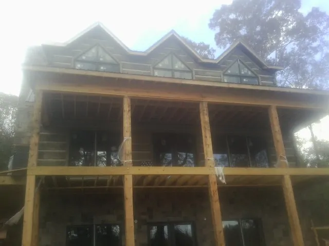 Dormers and porch framing on a large log home under construction — Roof Coating work by our crew in Watkins