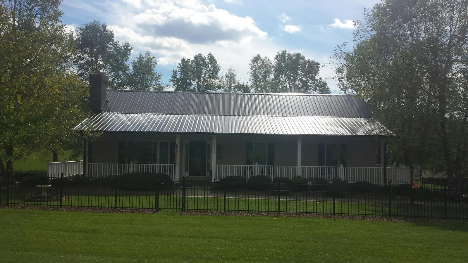 Gray metal roof on a brick ranch with a full width front porch — Gutter Guard Installation work by our crew in Watkins